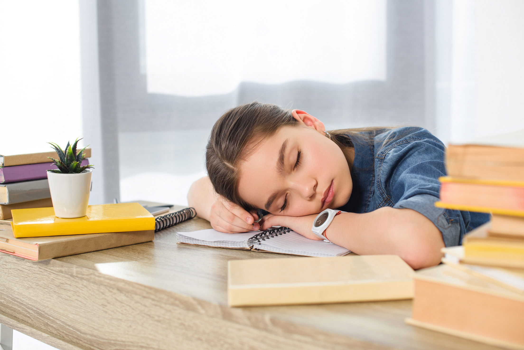 adorable preteen child sleeping on books at home