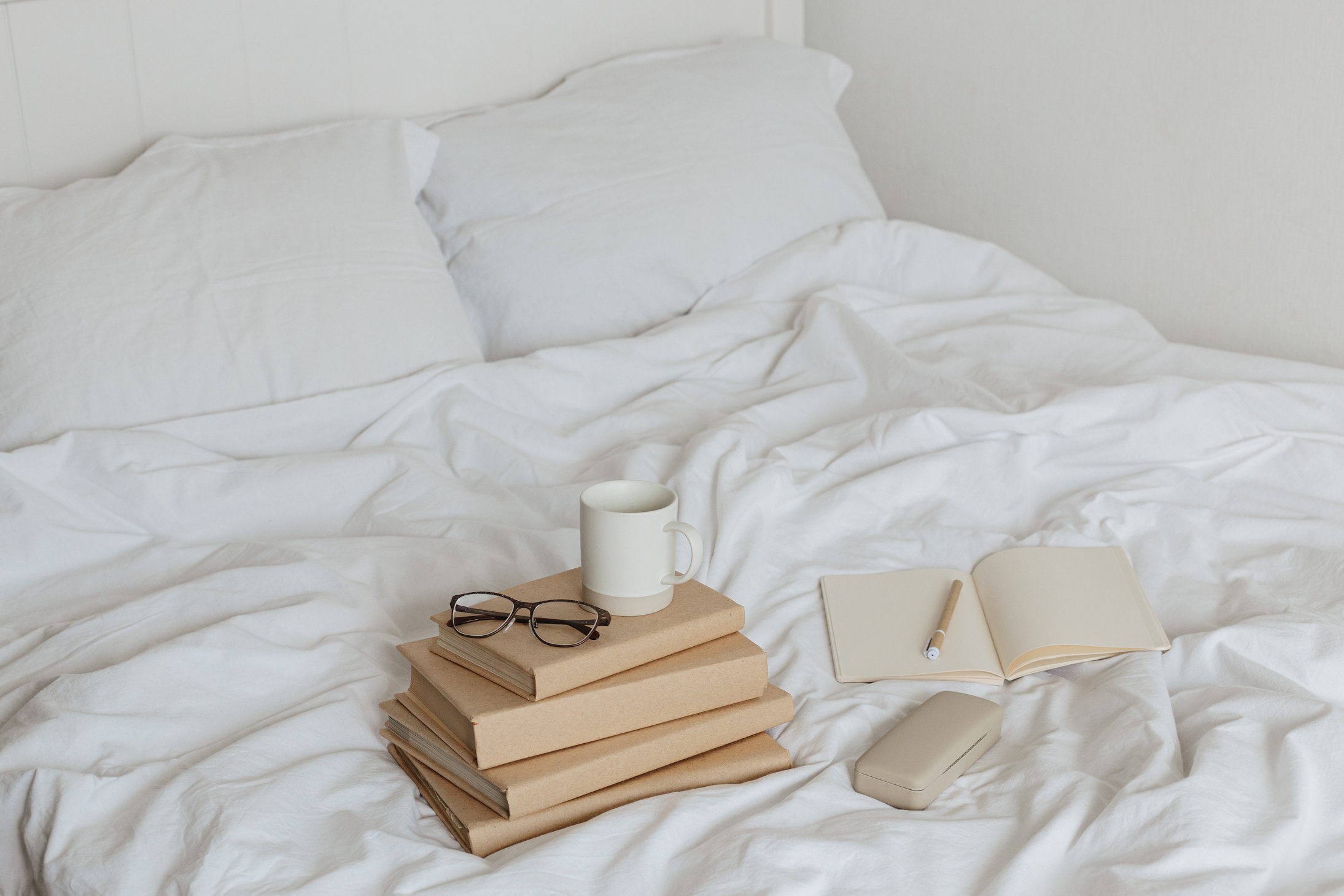 Books on bed white bed linen.