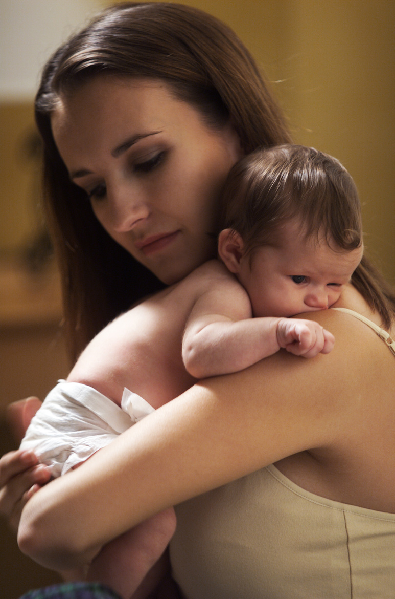 a young caucasian mother holds her newborn baby close